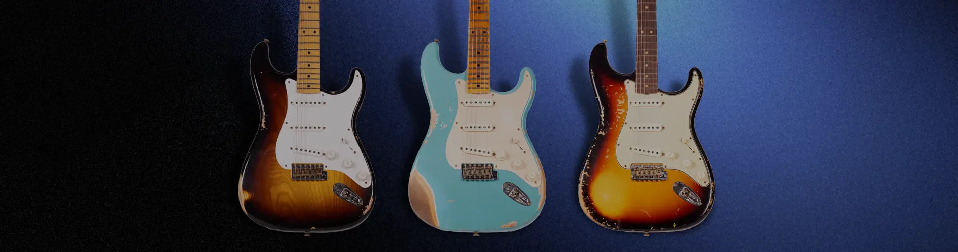 3 guitarras customizadas recargadas sobre una pared azul oscura